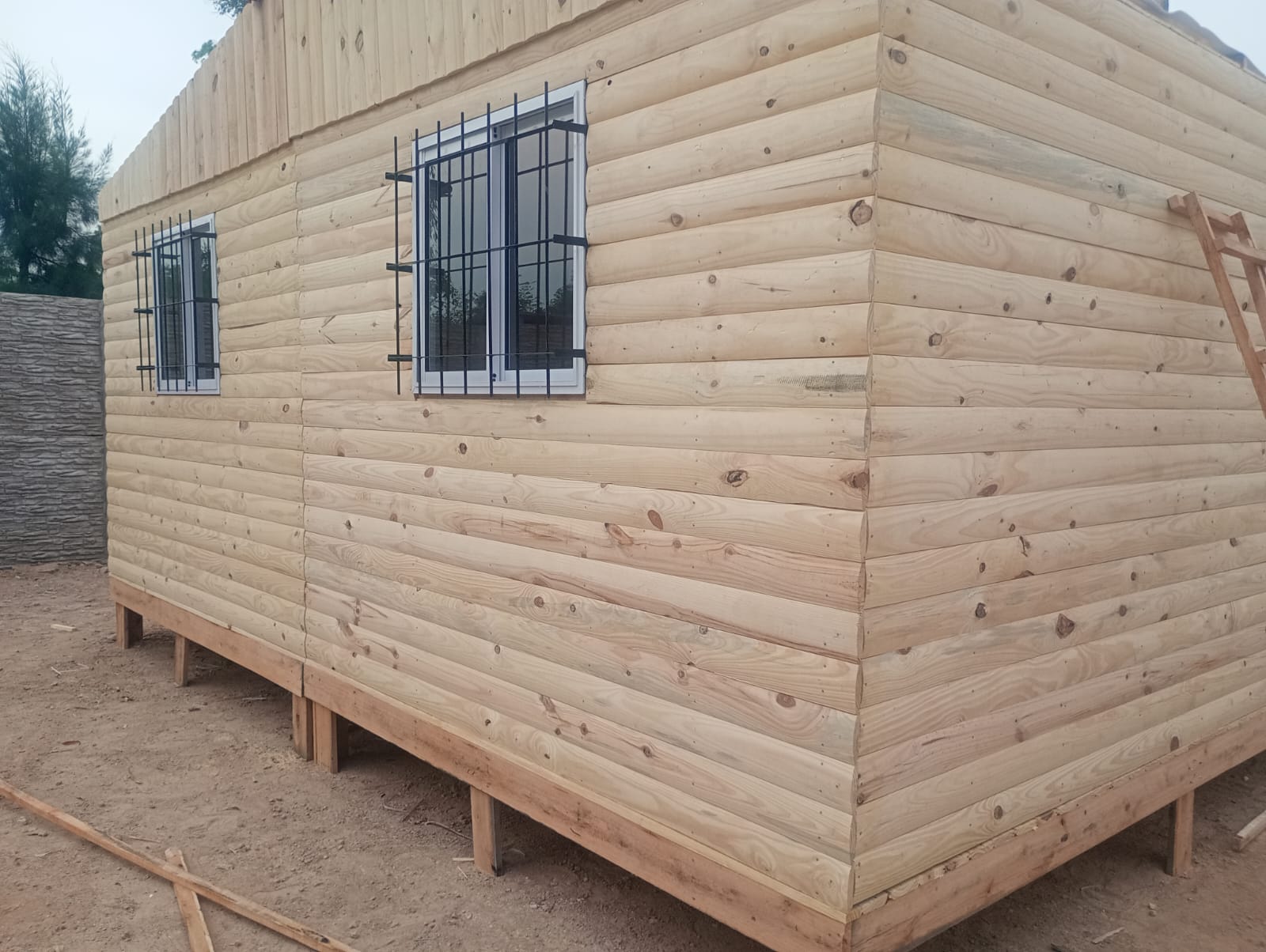 Vivienda de madera con ventanas de aluminio con rejas colocadas, foto real del fabricante