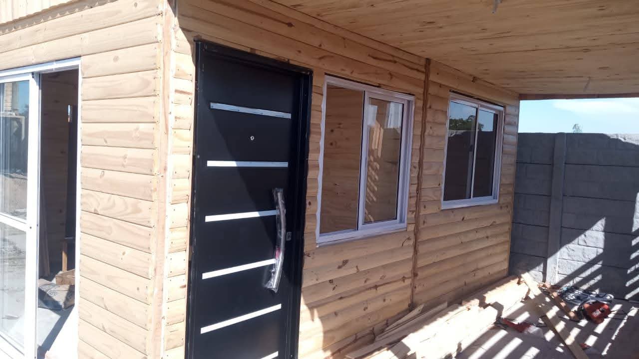 Cabaña de madera real con galería techada y aberturas de aluminio